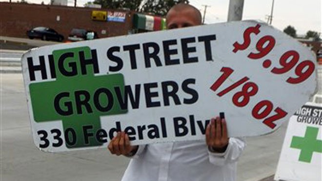 A sign-spinner outside a west Denver medical marijuana dispensary advertises low-cost pot as rush hour drivers pass the pot shop on Monday, Aug. 13, 2012. The spinner, who wouldn’t give his name, could be out of a job under an outdoor advertising ban was approved by the Denver City Council. (AP Photo/Kristen Wyatt)